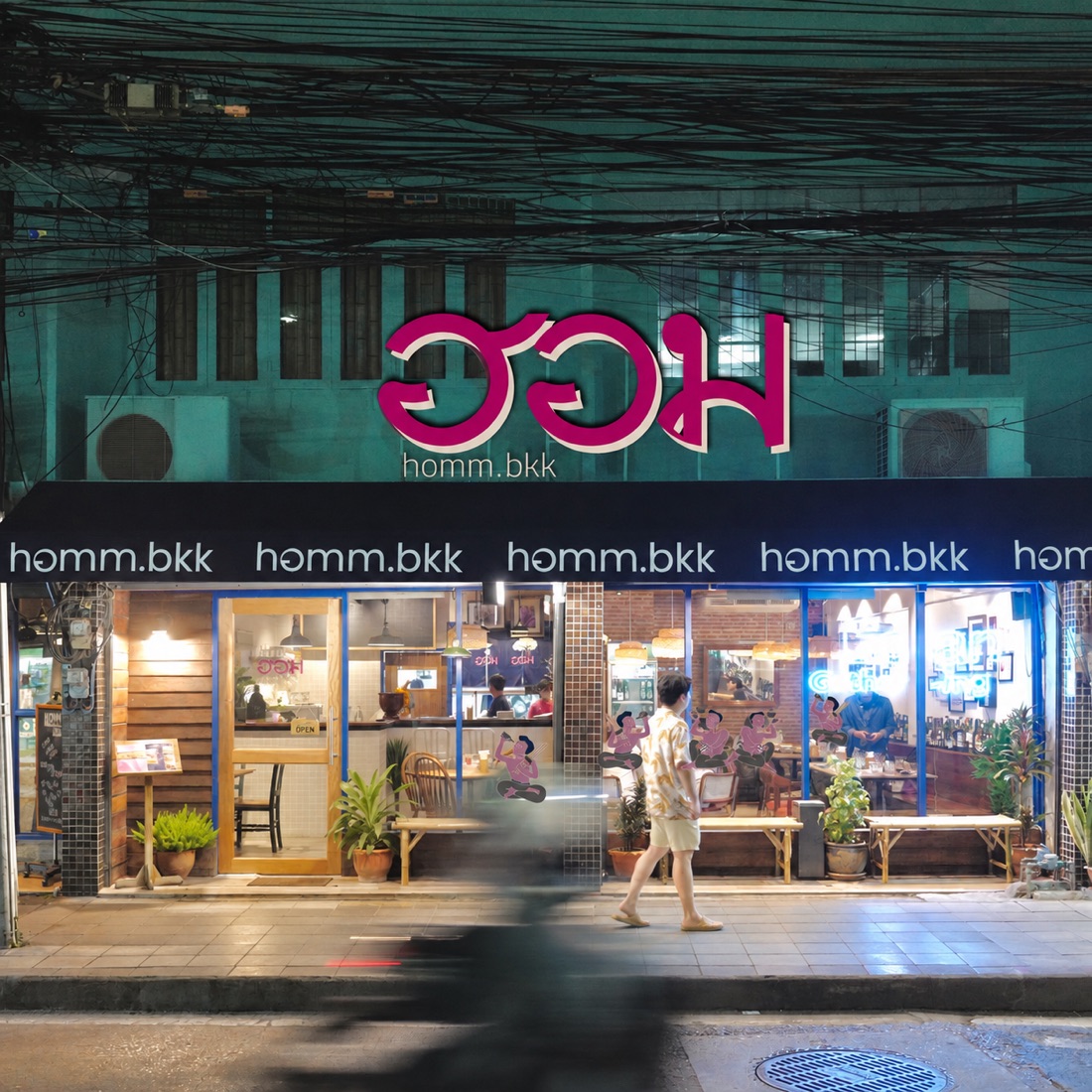 homm.bkk storefront at night with its pink neon sign