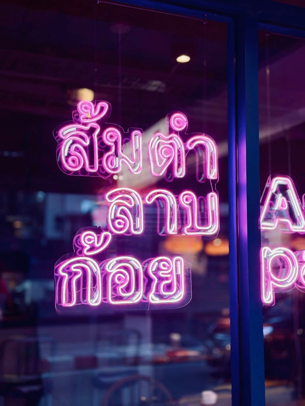 Pink Thai neon sign in the window of homm.bkk
